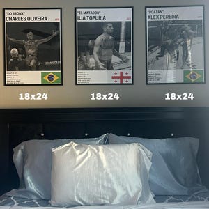three framed posters of professional boxers, each with a different fighter's name and image, displayed above a bed with white pillows.