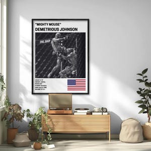 a framed poster of Demetrius Johnson, a professional mixed martial artist, hanging on a wall in a room with a wooden table and various plants.
