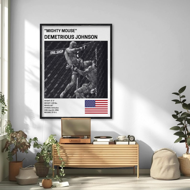 a framed poster of Demetrius Johnson, a professional mixed martial artist, hanging on a wall in a room with a wooden table and various plants.