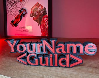 May include: A 3D printed sign with the text "YourName <Guild>" in black with red lettering. The sign is on a wooden surface.
