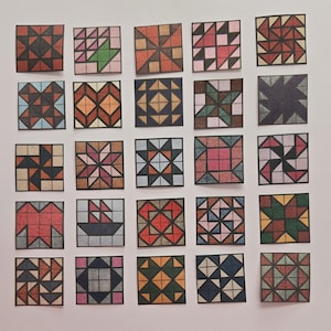 May include: A collection of 25 small, square paper cutouts, each featuring a unique quilt block design. The blocks showcase various geometric patterns in a range of colors, including red, blue, green, and brown, with black outlines.