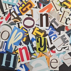 May include: A collection of assorted paper cutouts featuring various letters of the alphabet in different fonts, sizes, and colors. The letters are scattered in a dense, overlapping arrangement, showcasing a mix of serif, sans-serif, and decorative styles.