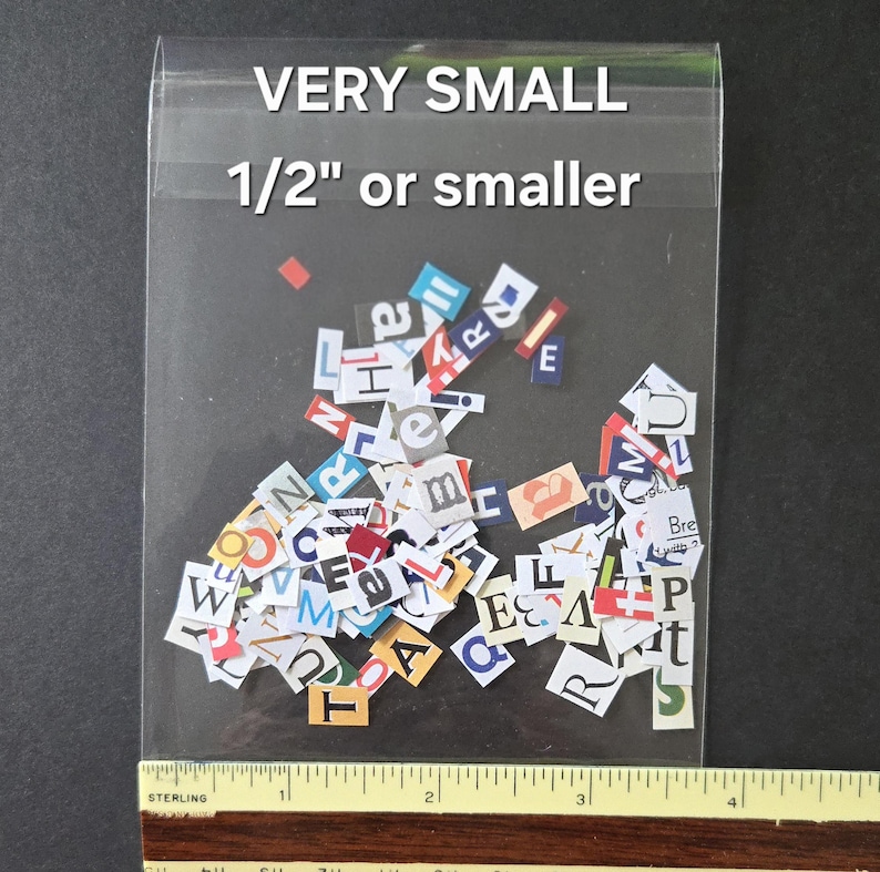 May include: A clear plastic bag containing a collection of small, multicolored paper cutouts of individual letters and characters. The text on the bag reads VERY SMALL 1/2" or smaller. A yellow ruler is positioned at the bottom for scale.