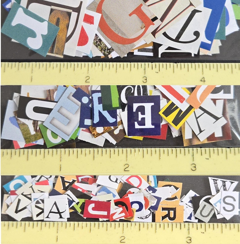 May include: A collection of assorted paper letter cutouts in various fonts, colors, and sizes, arranged in three horizontal rows. A yellow ruler is visible, showing the letters range from approximately 0.25 to 1.5 inches in height.