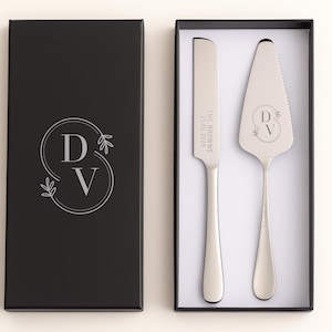 May include: A wedding cake serving set in a black gift box. The set includes a cake knife and server with engraved initials and date. The box has a matching monogram design. A perfect gift for a wedding or anniversary.
