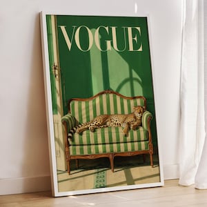 May include: A framed wall art print featuring a green and white striped settee with a cheetah resting on the cushions. The background is a solid green wall with a door frame on the left. The word VOGUE is printed in large white capital letters at the top.