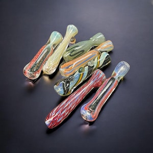 May include: A collection of colorful glass smoking pipes with intricate patterns and swirls. The pipes are made of clear glass with various colors, including red, blue, green, and yellow.
