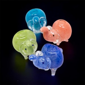 May include: Four small glass elephant pipes in different colors: light blue, green, pink, and blue with white swirls.