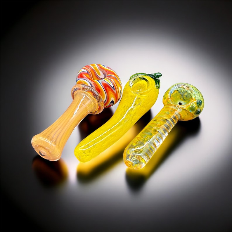 Peut inclure: Trois pipes &agrave; fumer en verre avec des motifs color&eacute;s. Les pipes sont jaunes, orange et vertes. Les pipes sont en verre et ont un bol arrondi.