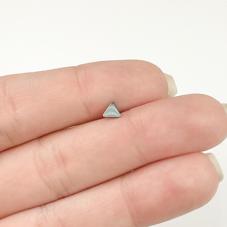 May include: A silver triangle stud earring.