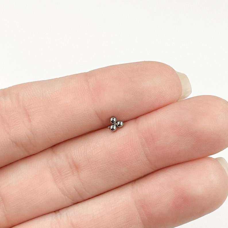 May include: A silver three-ball stud earring for body piercing.