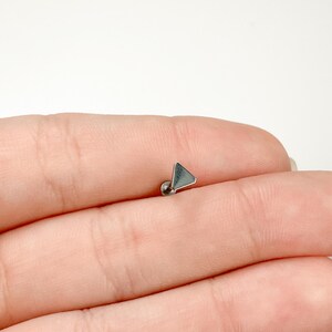 May include: A silver triangle stud earring with a flat back.