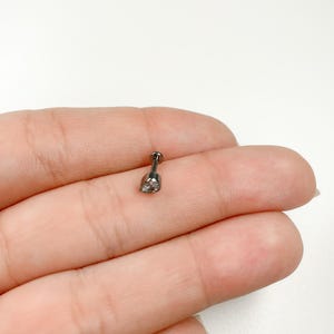 May include: A black stud earring with a small clear stone in the center.