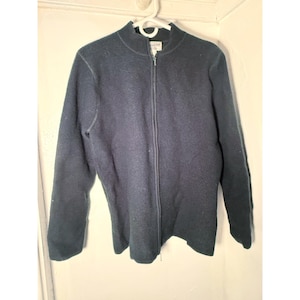 Puede incluir: Chaqueta azul marino con cremallera y cuello alto. La chaqueta está hecha de un material texturizado y cuelga de una percha blanca. El nombre de la marca "Pendleton" es visible en el cuello.