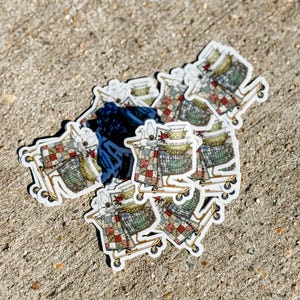 May include: A collection of stickers featuring a shopping cart design. The cart is filled with various items, including a quilt, dishes, and a goose figurine. The stickers have a white border and are scattered on a textured surface.