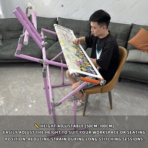 May include: A light purple, height-adjustable embroidery stand, with a colorful needlepoint project in progress. The stand's height adjusts from 19.7 to 39.4 inches. The text on the image reads: "HEIGHT ADJUSTABLE (50CM-100CM) EASILY ADJUST THE HEIGHT TO SUIT YOUR WORKSPACE OR SEATING POSITION, REDUCING STRAIN DURING LONG STITCHING SESSIONS."
