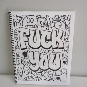 May include: Spiral-bound sketchbook with a black and white doodle art design. The words "FUCK YOU" are prominently displayed in bold, bubble letters. The background is filled with cartoonish faces and shapes.