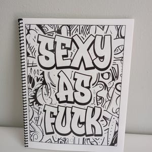 May include: A spiral-bound sketchbook with a black and white graffiti-style design. The words "SEXY AS FUCK" are prominently displayed in bold, outlined letters against a backdrop of abstract doodles and patterns.