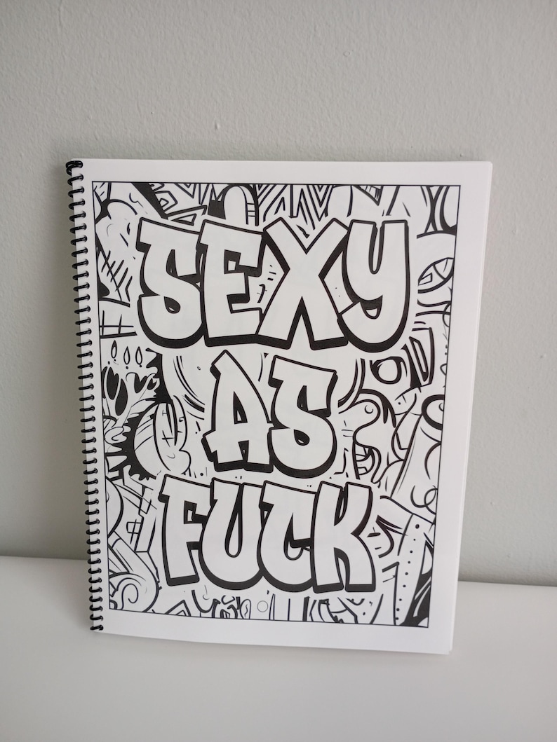 May include: A spiral-bound sketchbook with a black and white graffiti-style design. The words "SEXY AS FUCK" are prominently displayed in bold, outlined letters against a backdrop of abstract doodles and patterns.