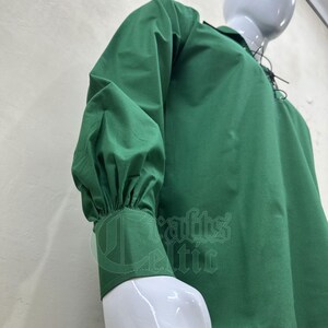 Pu&ograve; includere: Una camicia verde a maniche lunghe con colletto a lacci e maniche a sbuffo. La camicia &egrave; realizzata in morbido tessuto di cotone.