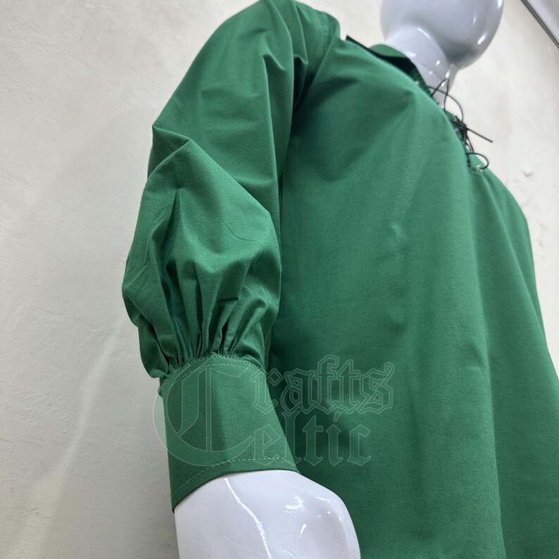 Pu&ograve; includere: Una camicia verde a maniche lunghe con colletto a lacci e maniche a sbuffo. La camicia &egrave; realizzata in morbido tessuto di cotone.