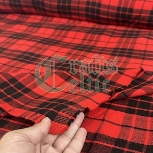 Pode incluir: Close-up de tecido xadrez vermelho e preto. O tecido exibe um padrão tecido clássico de linhas que se cruzam. O tecido é vermelho vibrante com linhas pretas formando um design xadrez tradicional. O tecido está dobrado, revelando a borda.