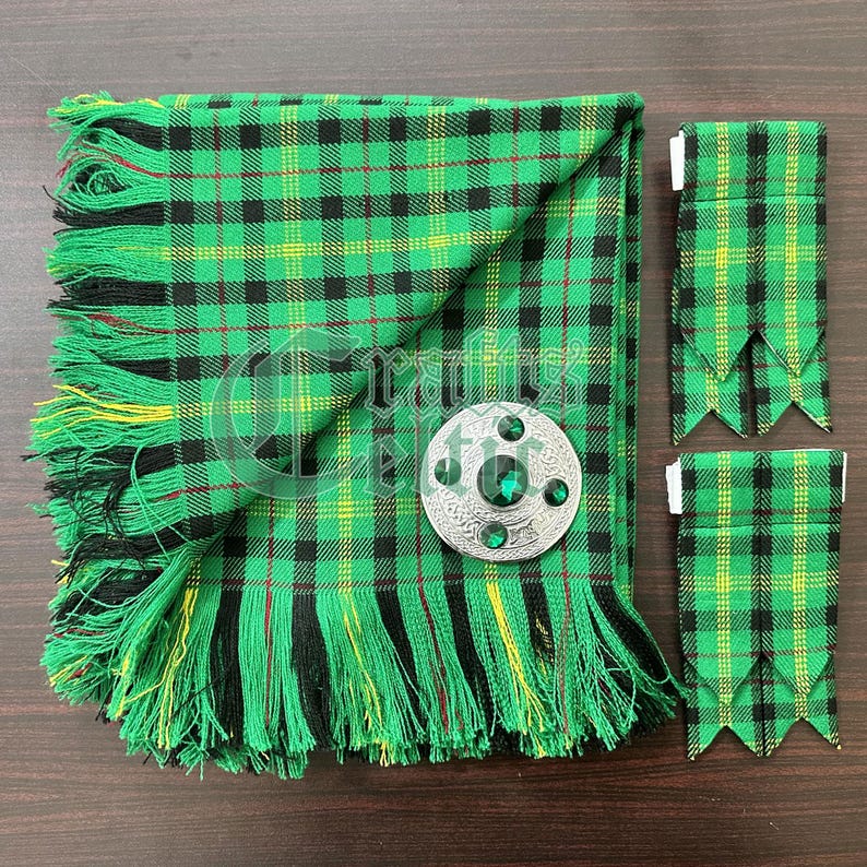 May include: A green, black, and yellow plaid kilt with a fringe border. The kilt is folded in half and a silver kilt pin with green stones is on top. Two matching green, black, and yellow plaid kilt hose are on the right side of the image.