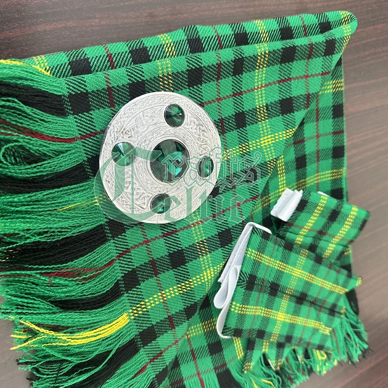 May include: A green, black, and yellow plaid kilt with a silver kilt pin featuring green gemstones. The kilt has a fringe around the bottom.