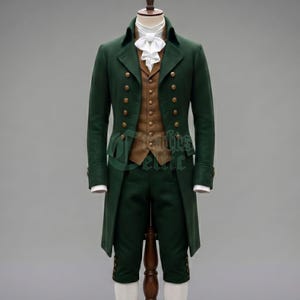 May include: A dark green tailcoat jacket with gold-toned buttons, paired with a tan vest featuring a single row of gold-toned buttons. The ensemble includes dark green knee-length breeches with gold-toned buttons and a white cravat at the neck.
