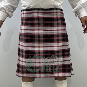 May include: A traditional kilt in a red, black, and white plaid pattern. The kilt is worn around the waist and has a fringed edge. The image shows the kilt from the waist down, with the text "Crafts Celtic" visible.