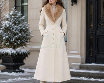 May include: A floor-length cream-colored wool coat featuring a large, fluffy faux fur collar in a tan shade. The coat has long sleeves, a fitted bodice, and a single row of small gold-toned buttons running down the front center.