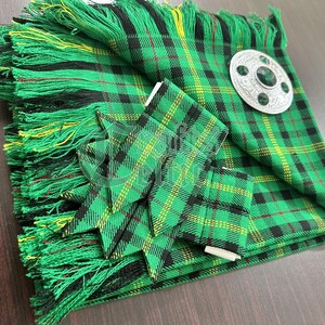 May include: A green, black, and yellow tartan kilt with a matching sash and a silver kilt pin with a green stone.