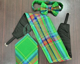 May include: A green, blue, and red plaid bow tie, pocket square, and kilt sash set. The sash is folded and has a black backing.