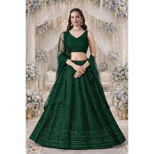 Puede incluir: Un vestido de noche de dos piezas verde oscuro con un top sin mangas y una falda amplia. El conjunto incluye un chal transparente. La tela está adornada con pequeños detalles brillantes. El vestido es adecuado para ocasiones especiales.
