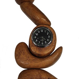 Op de afbeelding: Een houten klok met een ronde wijzerplaat en zwarte wijzers. De klok is gemaakt van verschillende stukken hout die op elkaar zijn gestapeld. De klok is een unieke en stijlvolle manier om de tijd te vertellen.
