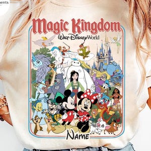 Puede incluir: Camiseta color crema con un gr&aacute;fico colorido de personajes de Disney y el texto "Magic Kingdom Walt Disney World". El dise&ntilde;o incluye Mickey y Minnie Mouse y otros personajes queridos.
