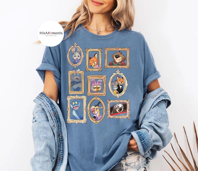 Puede incluir: Camiseta azul con retratos enmarcados de personajes de la pel&iacute;cula animada Zootr&oacute;polis. Los retratos est&aacute;n en marcos dorados e incluyen a Judy Hopps y Nick Wilde. La camiseta tiene el texto "HisMoments" en la parte superior izquierda.