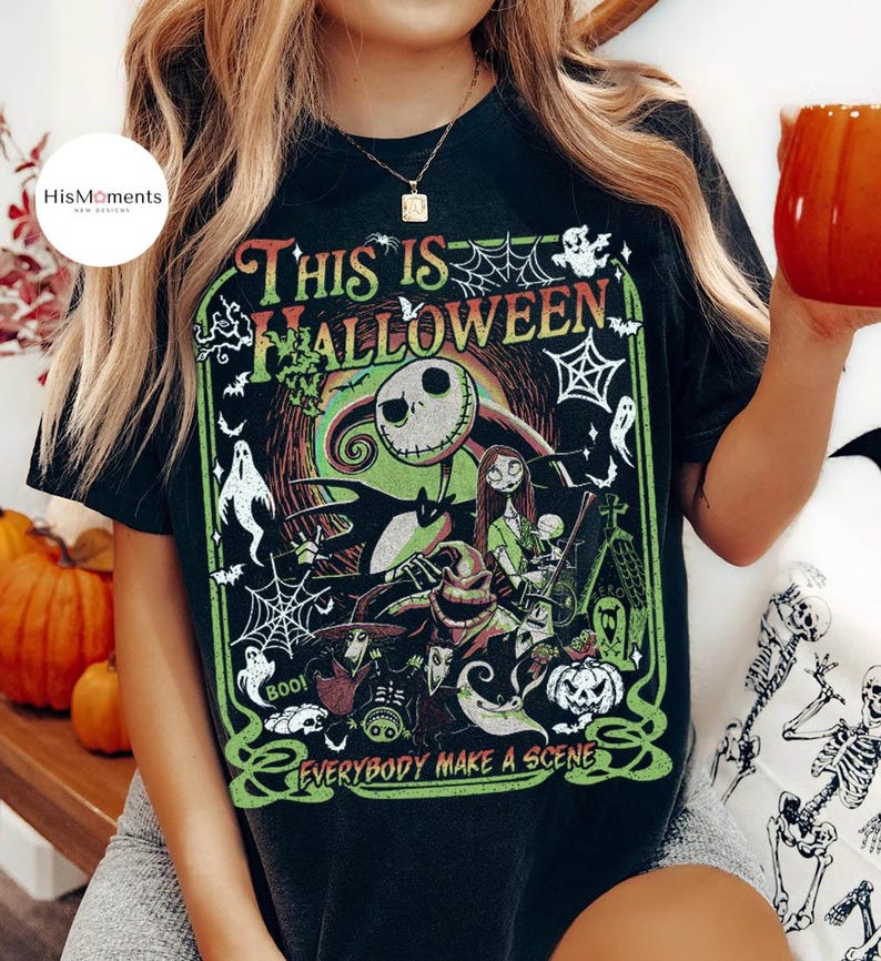 K&ouml;nnte beinhalten: Schwarzes T-Shirt mit einem farbenfrohen Grafikdesign aus "The Nightmare Before Christmas". Das Design zeigt Jack Skellington, Sally und andere Charaktere mit dem Text "This Is Halloween" und "Everybody Make a Scene" in Gr&uuml;n und Rot. Das Shirt hat einen Vintage-Look.