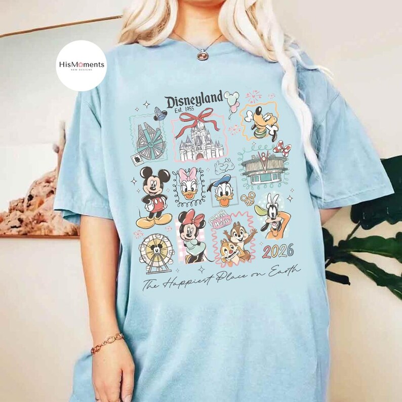 Peut inclure: T-shirt bleu clair avec un motif Disneyland, repr&eacute;sentant Mickey Mouse, Minnie Mouse et Donald Duck. Le t-shirt affiche le texte "Disneyland Est. 1955" et "The Happiest Place on Earth."
