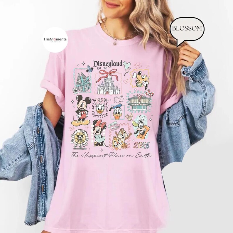 Peut inclure: T-shirt rose clair avec un motif Disneyland. Le motif comprend Mickey Mouse, Minnie Mouse, Donald Duck, Dingo et Tic et Tac, ainsi que le texte "Disneyland Est. 1955" et "The Happiest Place on Earth."