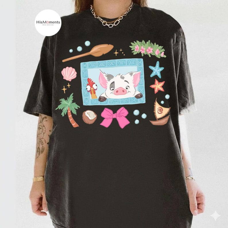 May include: Black graphic t-shirt featuring a cartoon illustration with a pig, chicken, and other tropical elements. The design includes a pink bow, starfish, and a small boat. The shirt has a relaxed fit and short sleeves.