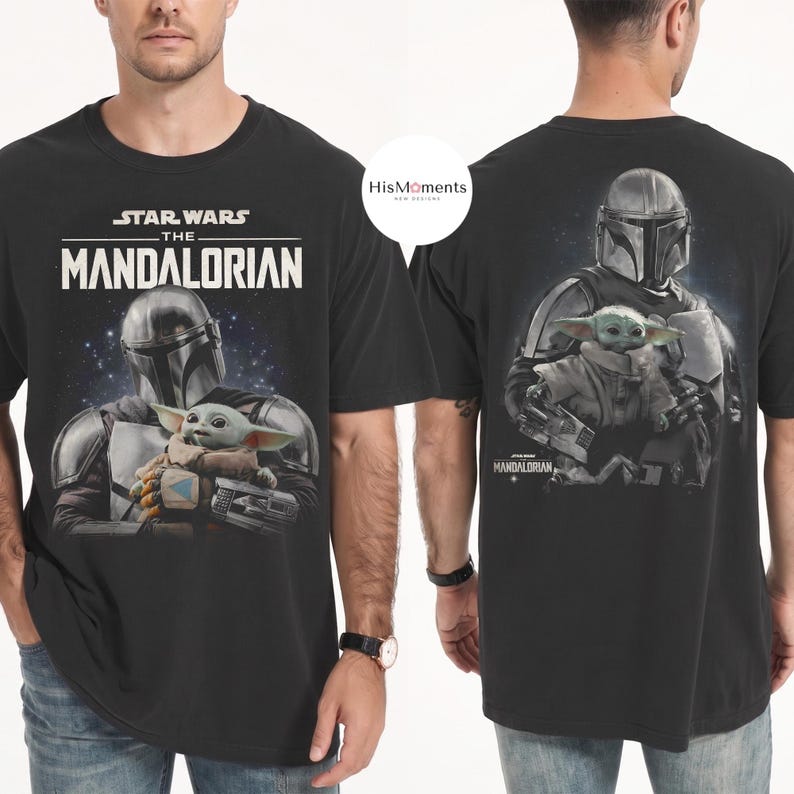 May include: Black t-shirt featuring a graphic of The Mandalorian and Grogu from Star Wars. The front of the shirt displays the text "STAR WARS THE MANDALORIAN" above the image. The back of the shirt shows the Mandalorian holding Grogu.