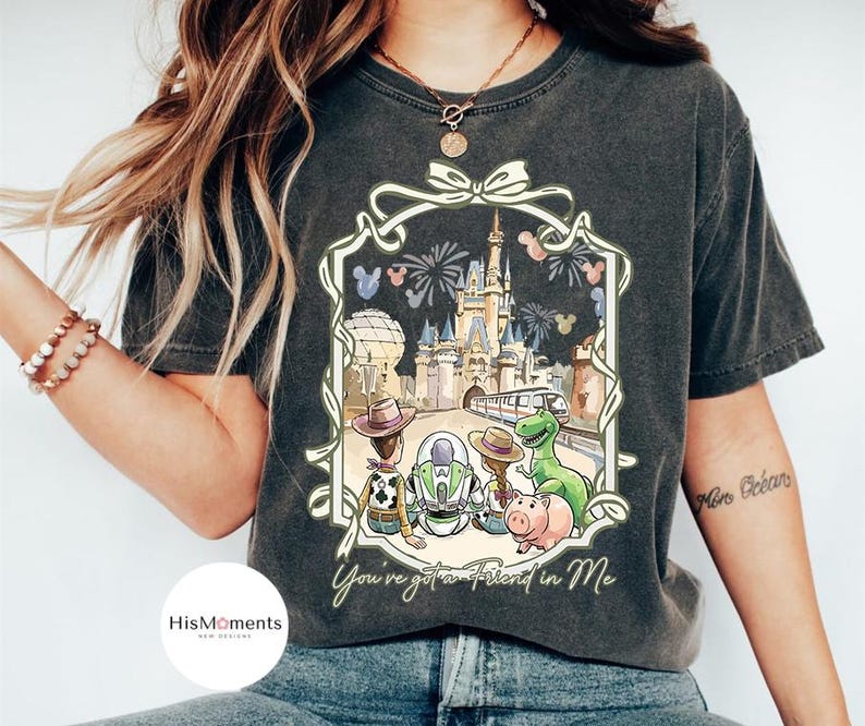 Peut inclure: T-shirt gris fonc&eacute; avec une illustration color&eacute;e de personnages Disney devant un ch&acirc;teau. L'image comprend le texte "You've got a Friend in Me" dans un cadre d&eacute;coratif. Le t-shirt est con&ccedil;u pour un usage d&eacute;contract&eacute;.