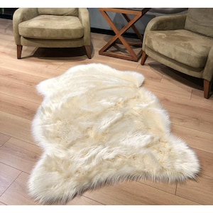 May include: A white faux fur rug with a shaggy texture. The rug is laid out on a wooden floor.