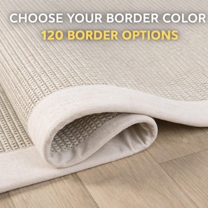 Può includere: Un tappeto beige arrotolato con un bordo colorato chiaro. Il tappeto ha un motivo a trama strutturata. Il testo in alto recita "CHOOSE YOUR BORDER COLOR" e "120 BORDER OPTIONS". Il tappeto è su un pavimento in legno chiaro.