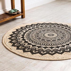 May include: A round jute rug with a black and white mandala design. The rug has a natural, woven texture.