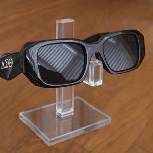 Op de afbeelding: Een witte keramische mok met een zwart handvat en de tekst "But First, Coffee" in een vetgedrukte, zwarte letter. De mok staat tegen een vage achtergrond. De mok is ongeveer 10 cm hoog.