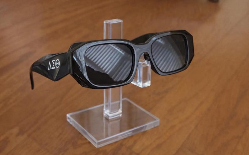 Op de afbeelding: Een witte keramische mok met een zwart handvat en de tekst "But First, Coffee" in een vetgedrukte, zwarte letter. De mok staat tegen een vage achtergrond. De mok is ongeveer 10 cm hoog.