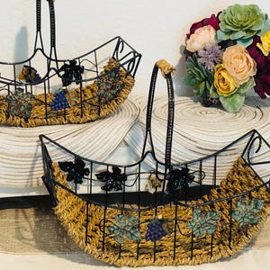 set of 2 decorative metal and woven rattan baskets with grapevine and floral accents.
