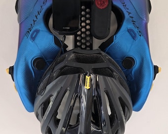May include: A collection of cycling gear, including blue and black cycling shoes, a black helmet, and a smartphone. The shoes are labeled "S-PHYRE". A black device and a red light are also visible.